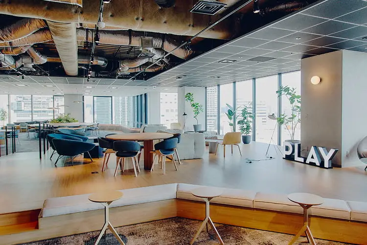モダンで広々としたオフィス空間に、様々なタイプの座席や大きな窓、そして「PLAY」の文字が配置されている様子