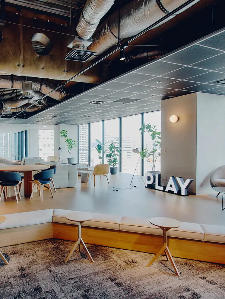 モダンなオフィスラウンジに設置された、明るく光る「PLAY」の文字のサイン