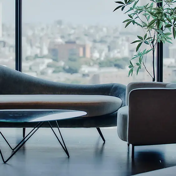 大きな窓から都市のスカイラインを望む、モダンなソファとコーヒーテーブルのあるラウンジ